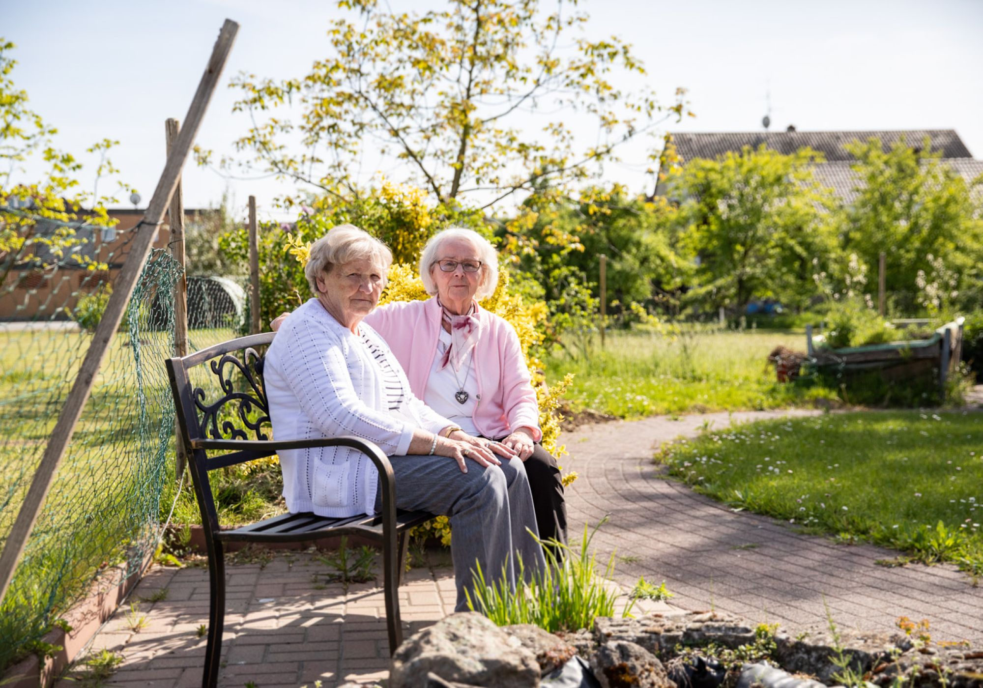 Zwei Klientinnen sitzen im Garten auf einer Bank